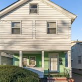 a view of a white house next to a yard