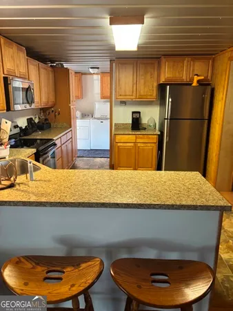 a kitchen with a refrigerator a stove top oven a sink a dining table and chairs