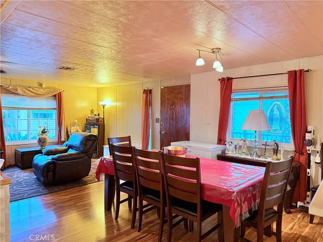 a view of a dining room with furniture one side kitchen view and wooden floor