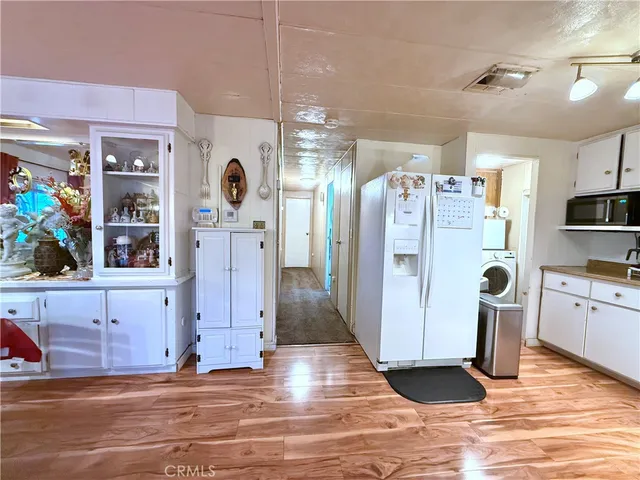 a view of a kitchen with refrigerator and wooden floor