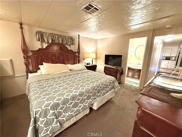 a bedroom with a large bed and a flat tv screen on dresser
