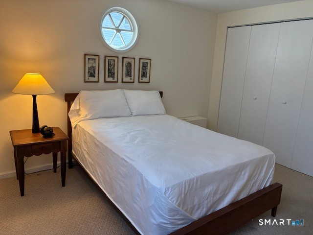 7 River Colony, Unit 7 Guilford, CT 06437 - Photo 15 of 23 a bedroom with a bed and a chandelier