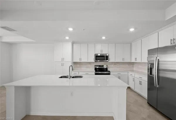 a kitchen with stainless steel appliances a table chairs and a refrigerator