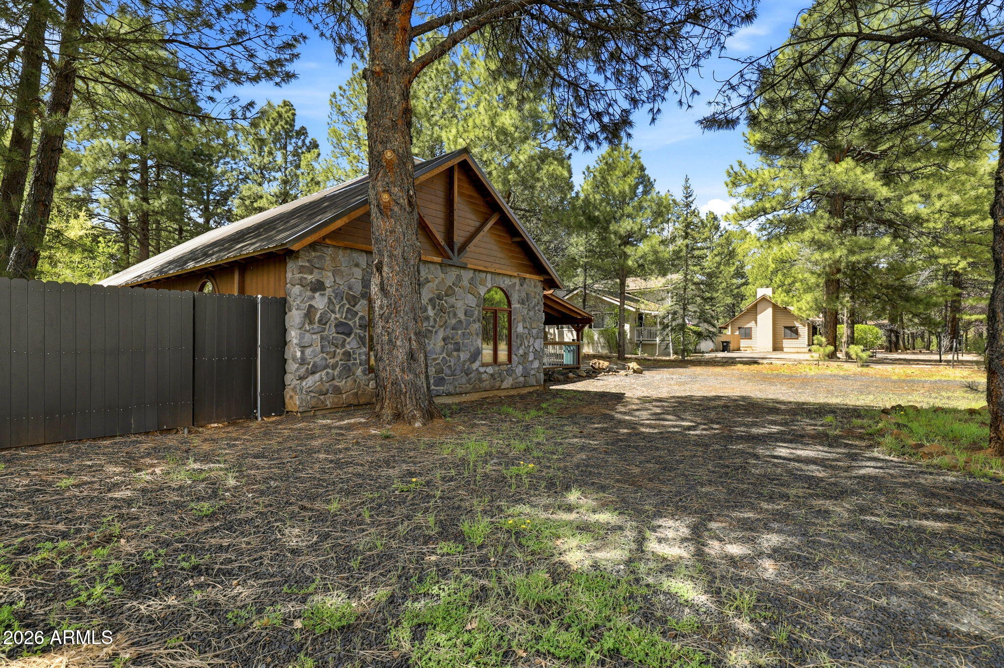 4971 Buck Springs Road Pinetop, AZ 85935 - Photo 29 of 32 a backyard of a house with large trees and wooden fence
