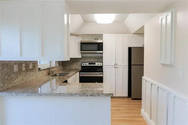a kitchen with granite countertop a refrigerator and a sink