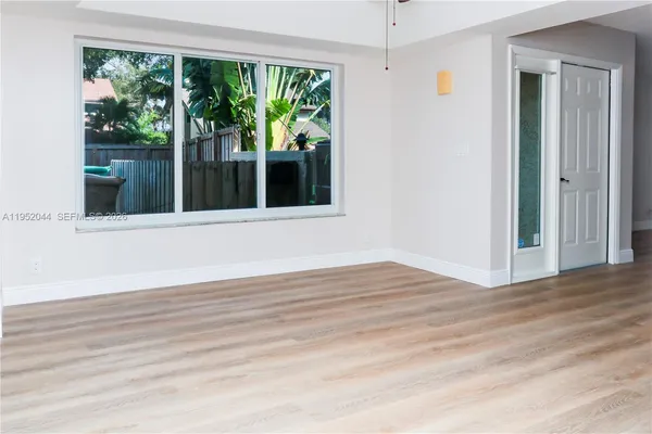 a view of an empty room with wooden floor and a window