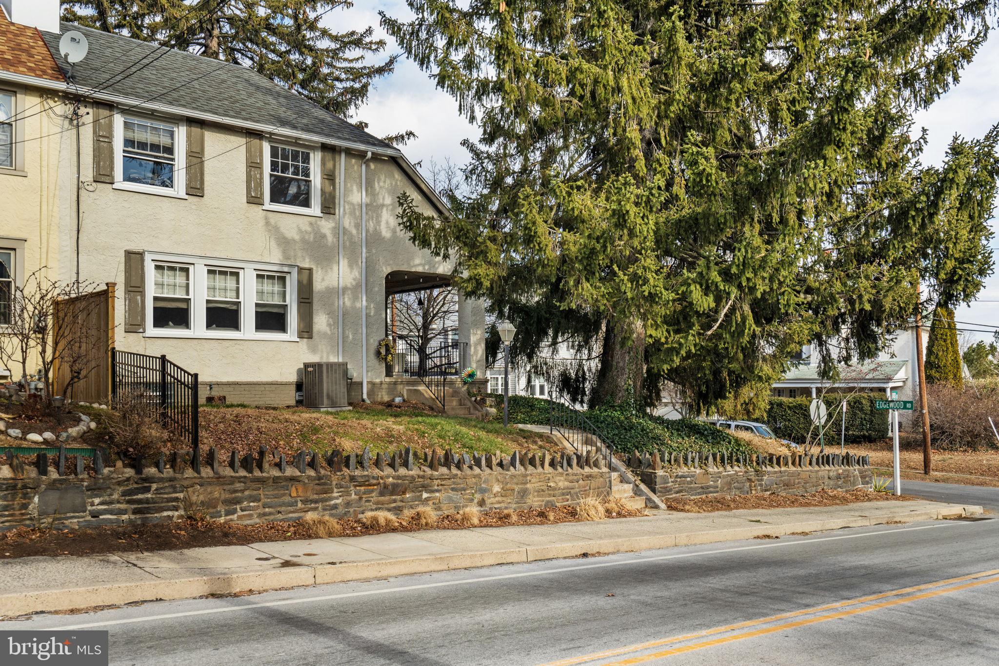 a view of a white house with large tree next to a road