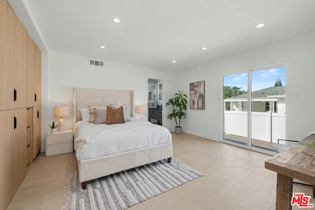 a large bedroom with a bed and wooden floor