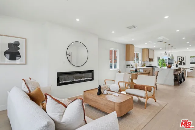 a living room with furniture a kitchen view and a clock