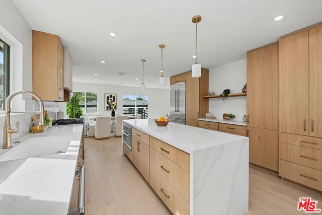 a large kitchen with stainless steel appliances a refrigerator a sink dishwasher and white cabinets with wooden floor