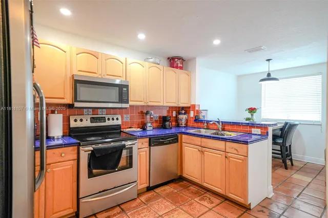 a kitchen with kitchen island granite countertop stainless steel appliances a sink counter space and a window