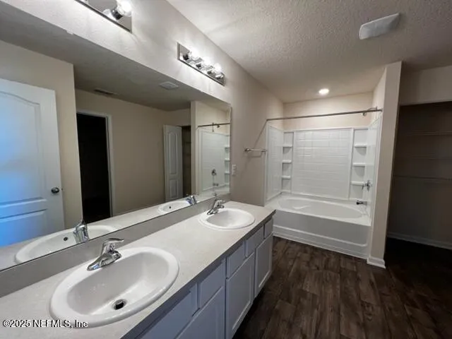 a bathroom with a double vanity sink a mirror and a bathtub