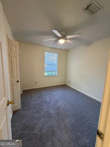 an empty room with windows and fan
