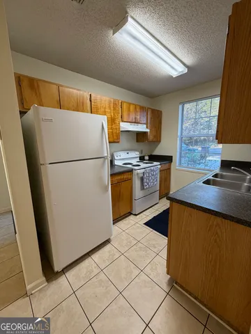 a kitchen with granite countertop a refrigerator stove top oven and sink