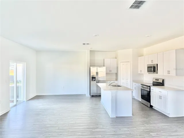 a kitchen with stainless steel appliances a stove top oven a sink dishwasher and a refrigerator with wooden floor