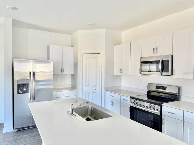 a kitchen with stainless steel appliances a refrigerator a sink a stove and cabinets