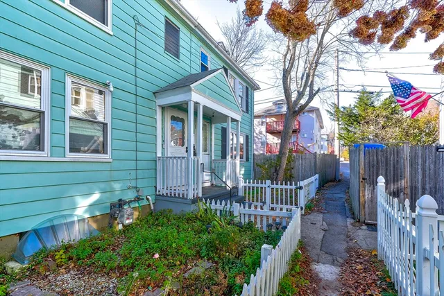 a view of a house with a small yard and wooden fence