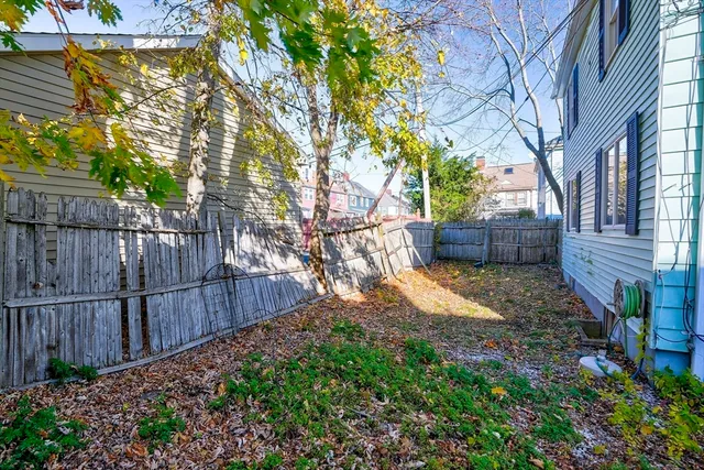 a view of backyard with wooden fence and large trees