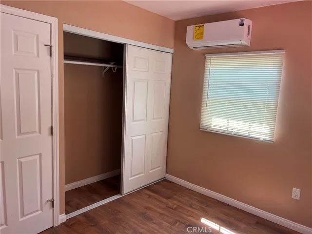 an empty room with wooden floor closet and windows