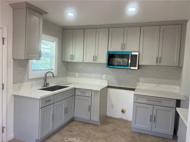 a kitchen with white cabinets appliances and sink