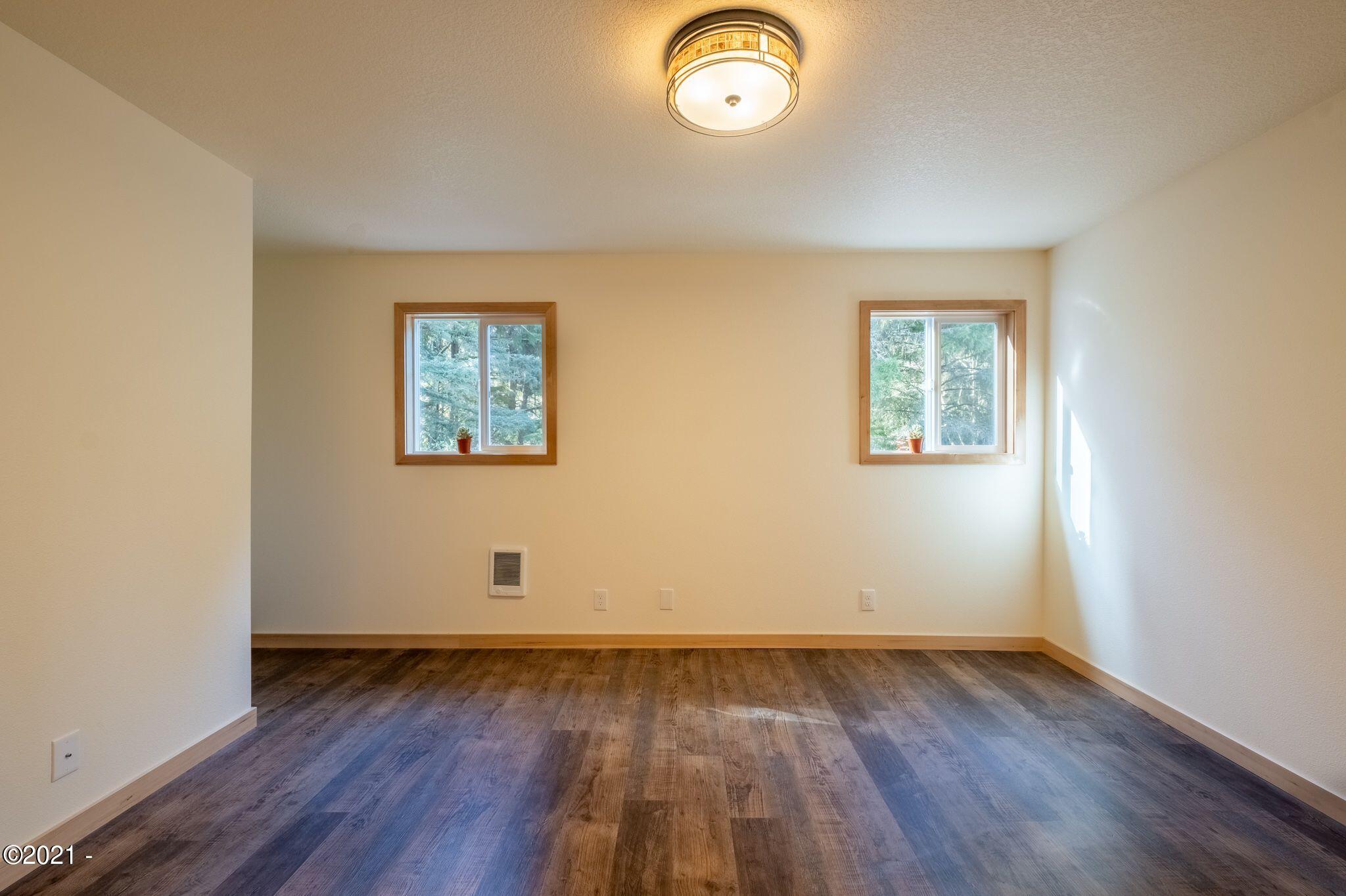 3048 Northeast East Line Road Yachats, OR 97498 - Photo 17 of 31 an empty room with wooden floor and windows