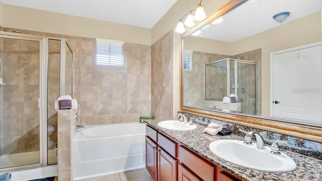 a bathroom with a granite countertop sink a mirror a bathtub and shower