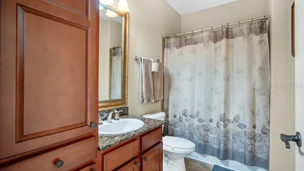 a bathroom with a granite countertop sink toilet and shower