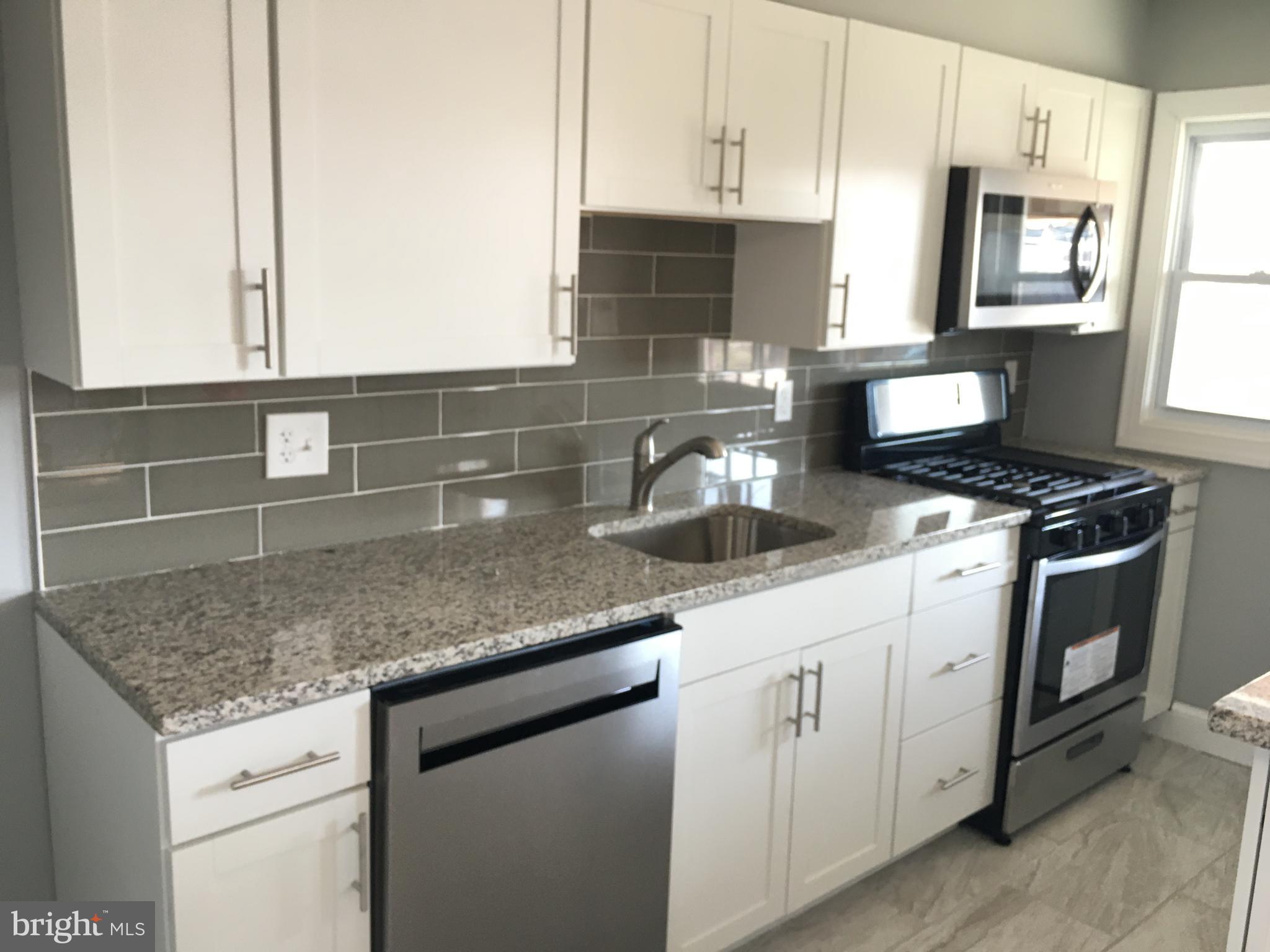 7441 Edsworth Road Baltimore, MD 21222 - Photo 12 of 37 a kitchen with granite countertop a sink a stove and cabinets