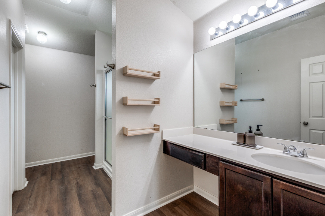 13708 Sierra Wind Lane Elgin, TX 78621 - Photo 13 of 19 Full primary bath featuring vanity, a stall shower, and dark wood-type flooring
