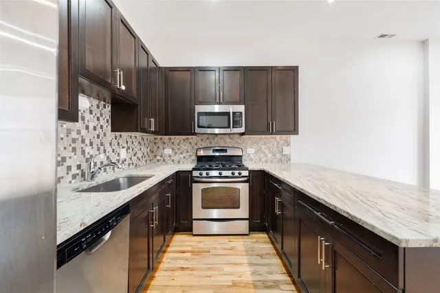 a kitchen with granite countertop stainless steel appliances and wooden cabinets