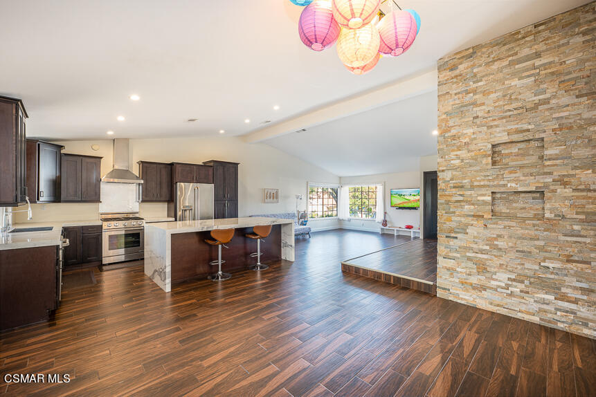 13680 Bear Valley Road Moorpark, CA 93021 - Photo 7 of 50 a kitchen with stainless steel appliances kitchen island granite countertop a stove top oven a dining table and chairs with wooden floor