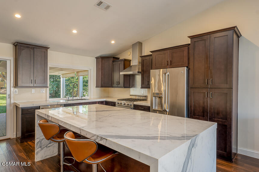 13680 Bear Valley Road Moorpark, CA 93021 - Photo 9 of 50 a kitchen with kitchen island a table chairs refrigerator and microwave