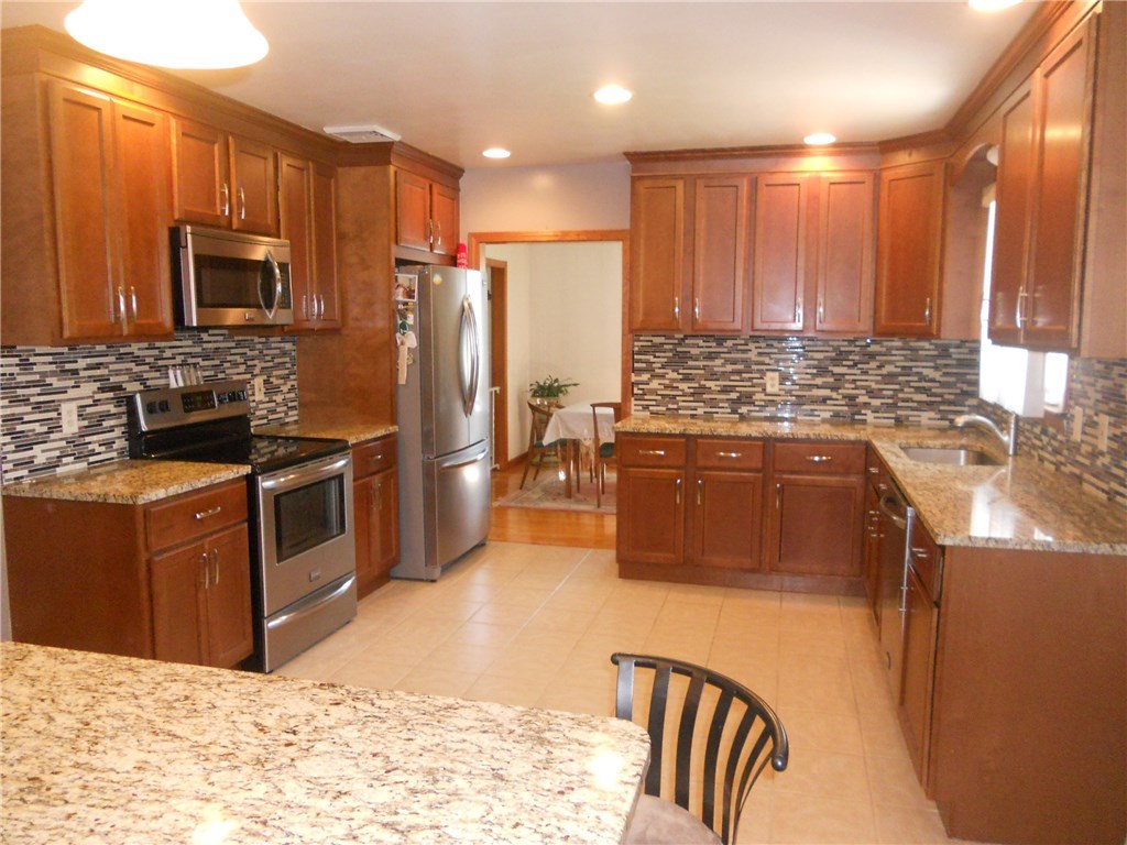 12 Lawrence Road North Providence, RI 02911 - Photo 21 of 40 LARGE 250 SQUARE FOOT KITCHEN WITH GRANITE EVERYWHERE, and backsplash. ALL MATCHING STAINLESS APPLIANCES, DEEP DOUBLE STAINLESS SINK, SHOWING VIEW TO FORMAL DINING ROOM. 5 3/4 FEET X 3 FEET GRANITE ISLAND COMFORTABLY SEATS 8 PEOPLE AROUND total of 29 kitchen cabinet doors and 8 drawers, in the kitchen, along with recessed lighting overhead