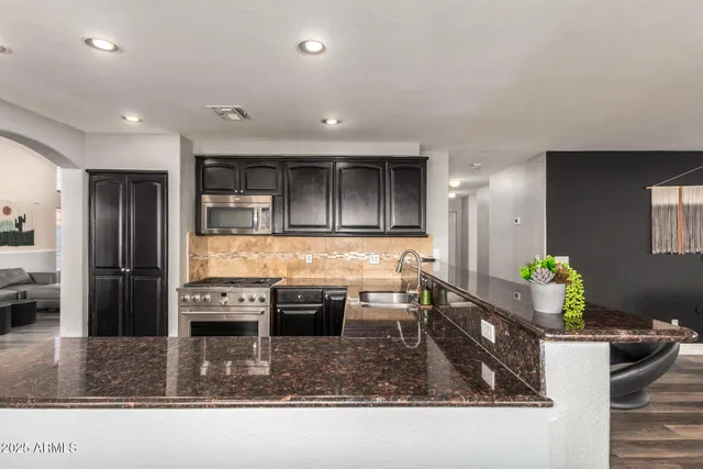 a kitchen with stainless steel appliances kitchen island granite countertop a refrigerator and a stove