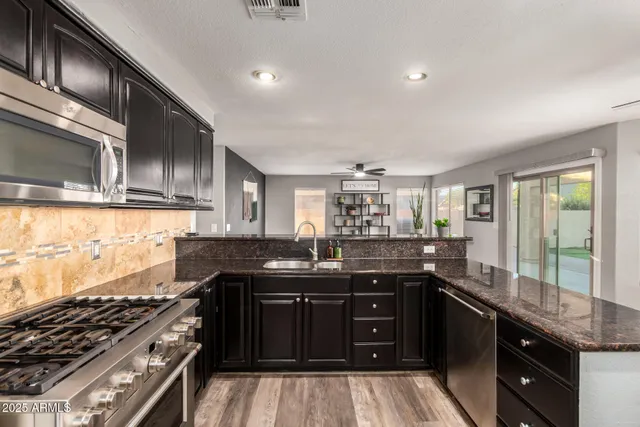 a kitchen with granite countertop stainless steel appliances a sink stove top oven and cabinets