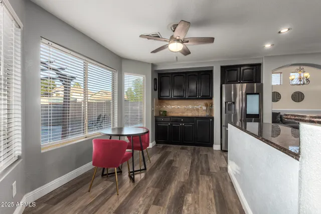 a kitchen with stainless steel appliances kitchen island granite countertop a refrigerator a stove a sink dishwasher with a dining table and chairs with wooden floor