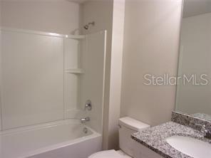 11357 Elgin Boulevard Spring Hill, FL 34608 - Photo 11 of 15 a bathroom with a granite countertop sink a toilet and shower