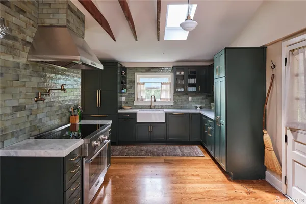 a kitchen with stainless steel appliances granite countertop a refrigerator a sink dishwasher a stove and white countertops with wooden floor