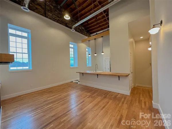 a view of an empty room with wooden floor and a fireplace