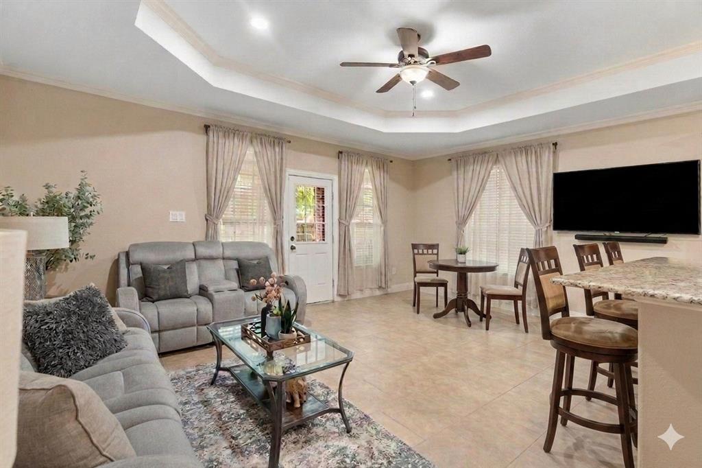 502 Ritchey Street Gainesville, TX 76240 - Photo 17 of 29 Spacious living area featuring a tray ceiling, ceiling fan, recessed lighting, tile flooring, and multiple windows