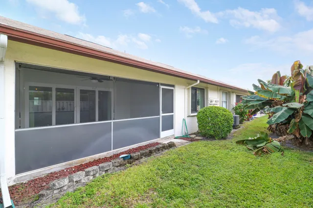 a front view of a house with a yard and potted plants