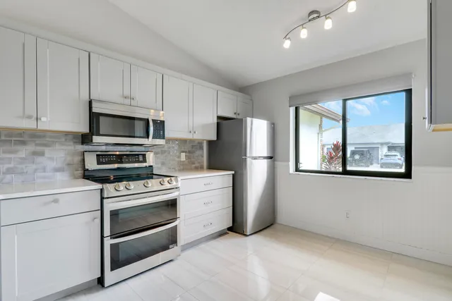 a kitchen with appliances a refrigerator and a stove top oven