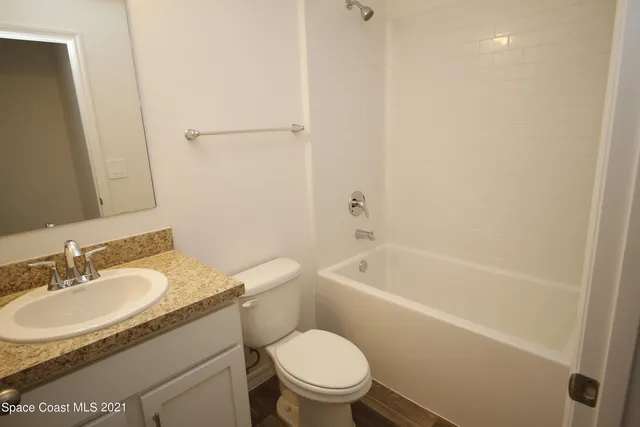 a bathroom with a granite countertop toilet a sink and a bathtub