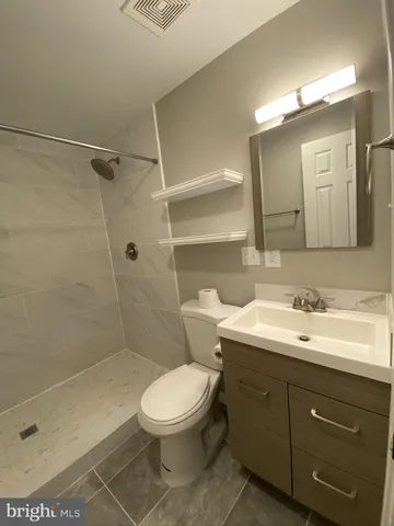 a bathroom with a toilet a sink a mirror and shower