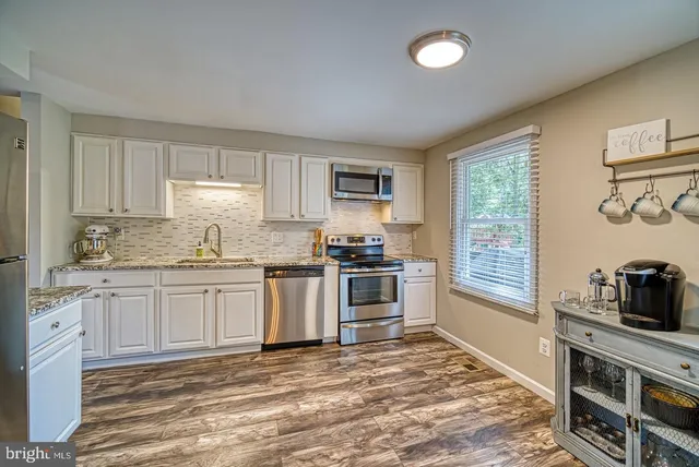 a kitchen with granite countertop white cabinets and stainless steel appliances