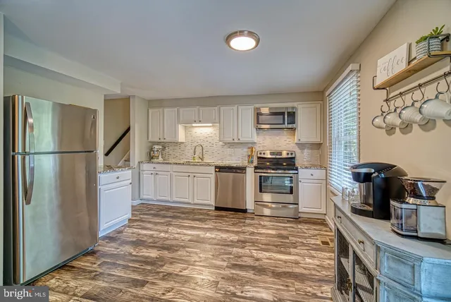 a kitchen with granite countertop a refrigerator stove top oven and sink