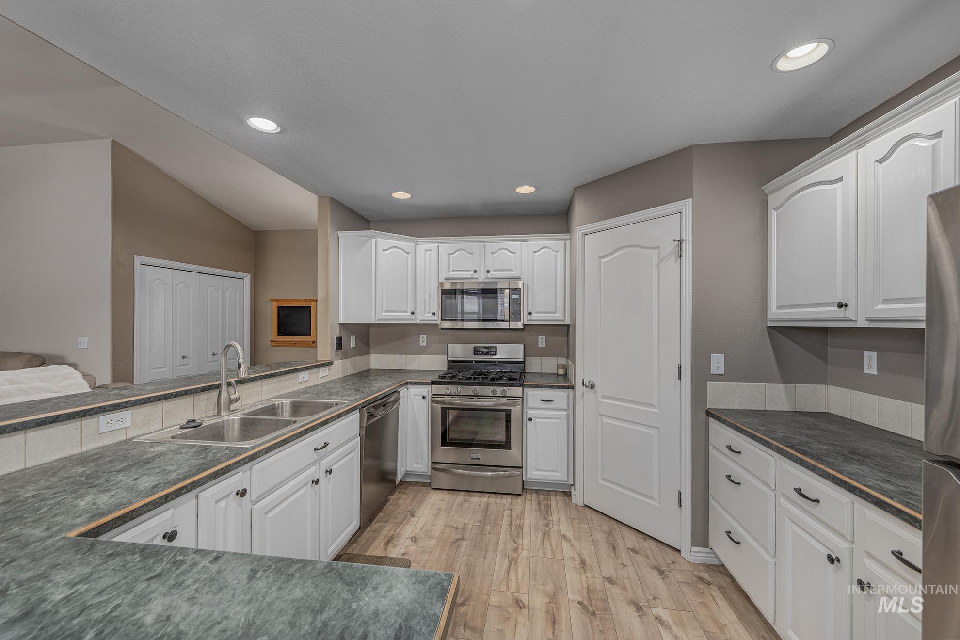 890 Jenkins Creek Road Weiser, ID 83672 - Photo 11 of 45 Kitchen with appliances with stainless steel finishes, white cabinets, light wood-type flooring, and recessed lighting