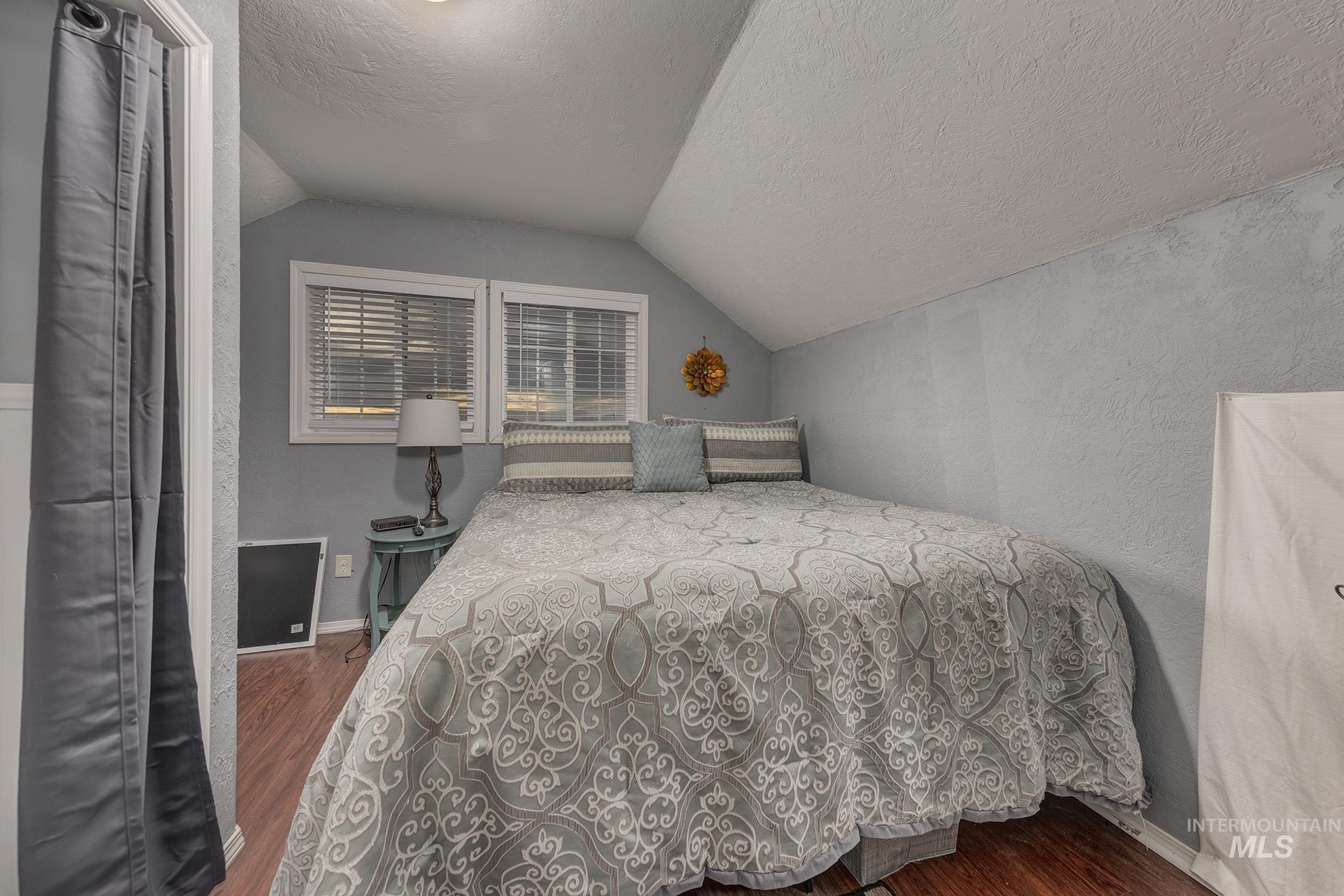 890 Jenkins Creek Road Weiser, ID 83672 - Photo 33 of 45 Bedroom with a textured ceiling, dark wood finished floors, vaulted ceiling, and a textured wall