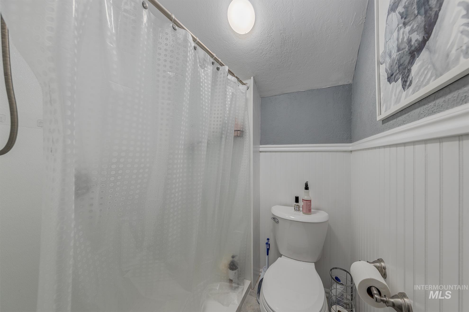890 Jenkins Creek Road Weiser, ID 83672 - Photo 34 of 45 Bathroom with curtained shower, a textured ceiling, a textured wall, and wainscoting