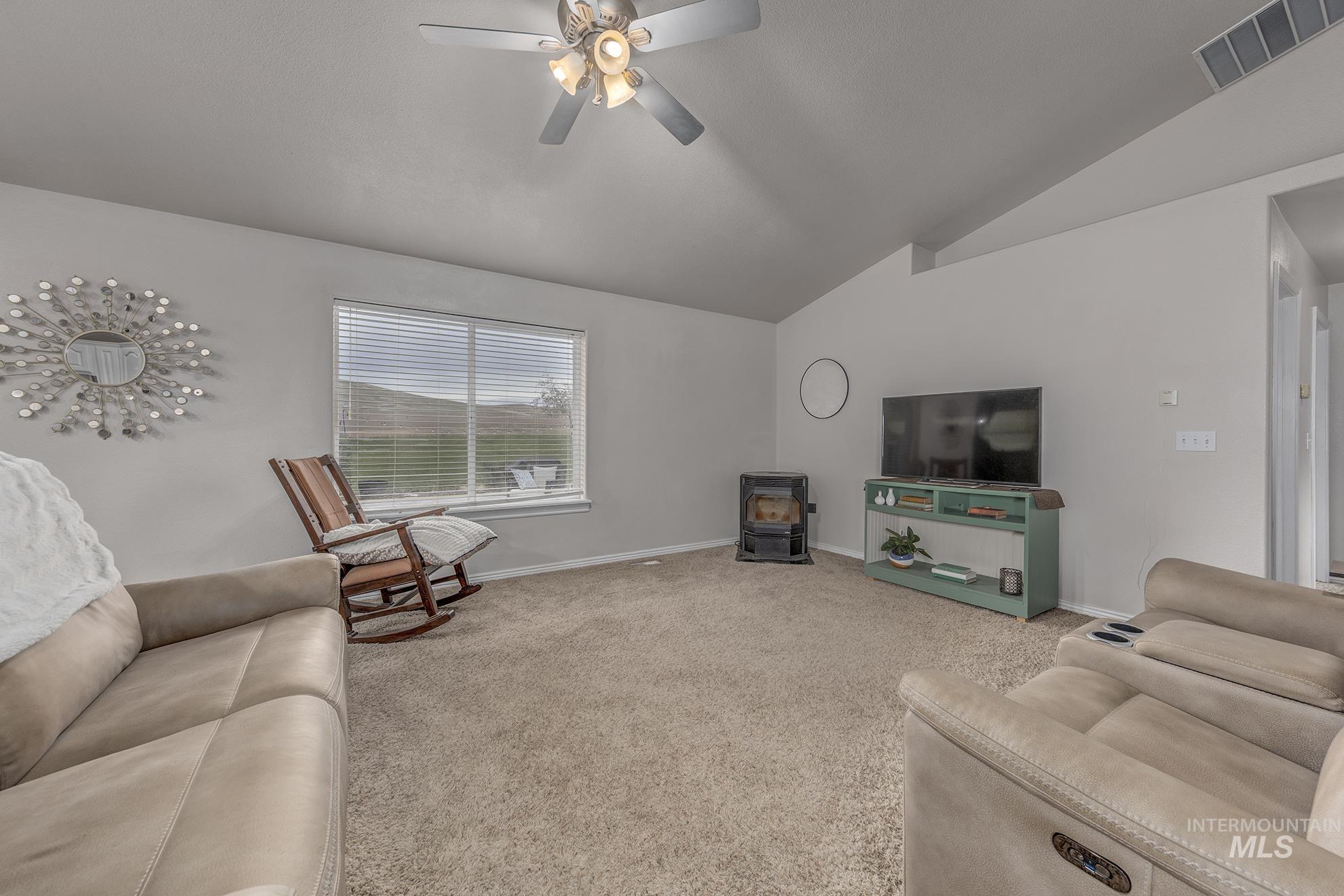 890 Jenkins Creek Road Weiser, ID 83672 - Photo 8 of 45 Living area featuring a wood stove, light colored carpet, lofted ceiling, and a ceiling fan